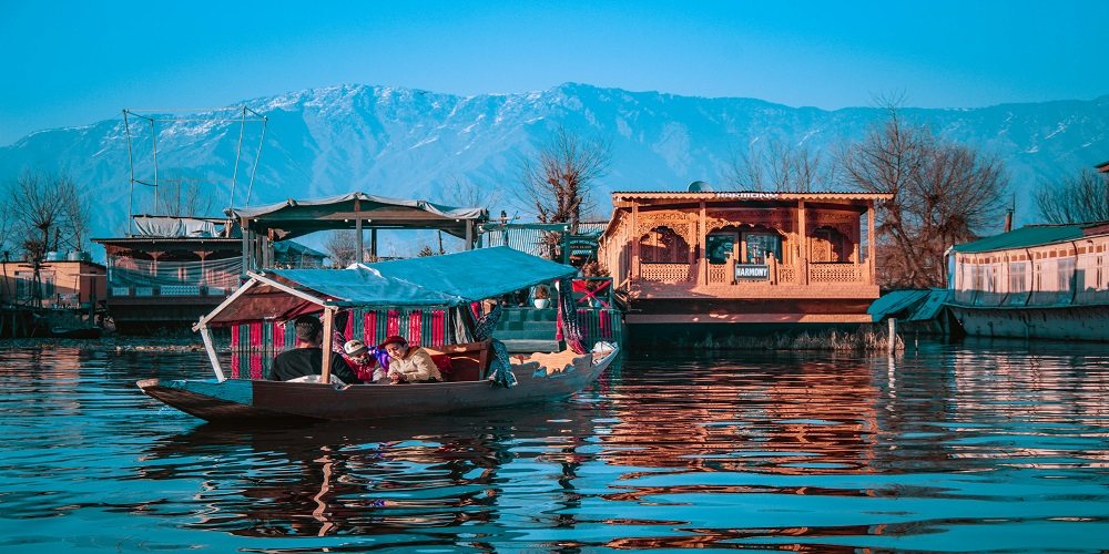 Kashmir — carved houseboats and a shikara on a still lake below hills