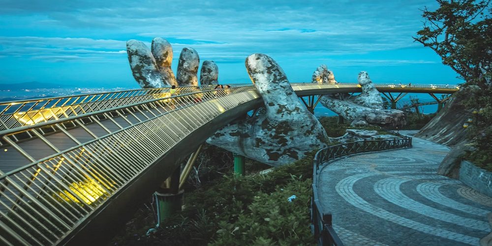 Vietnam — a curved footbridge over green water with mountains behind