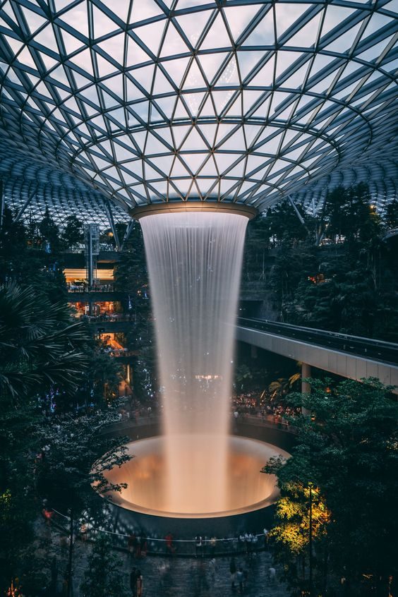 A waterfall falling through a ring inside a glass-domed garden