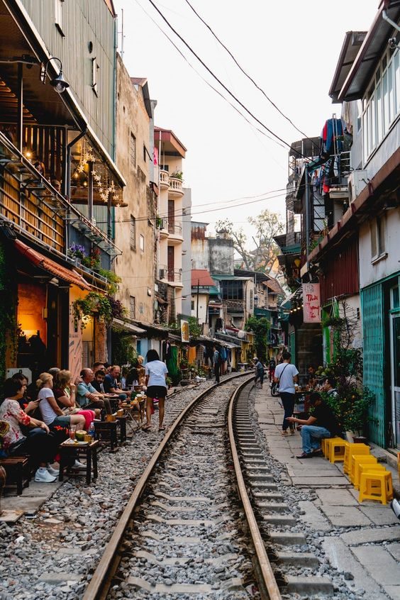 A narrow street where a railway line runs between cafés