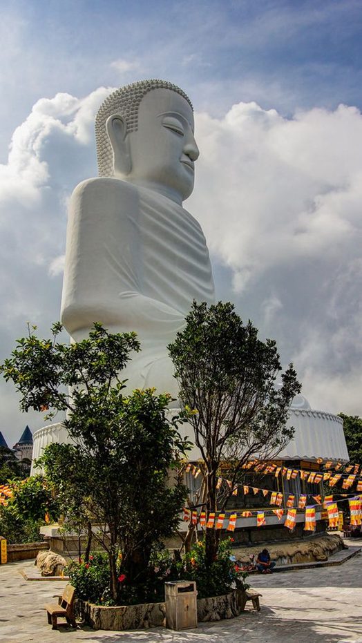 A great stone Buddha above a temple roof