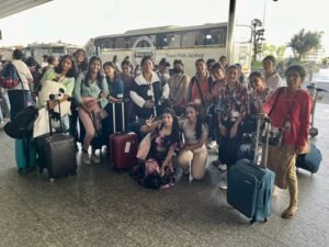 A school group with luggage photographed outside a station