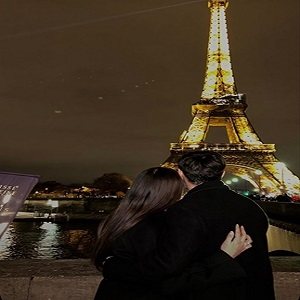 A couple in front of the Eiffel Tower at night