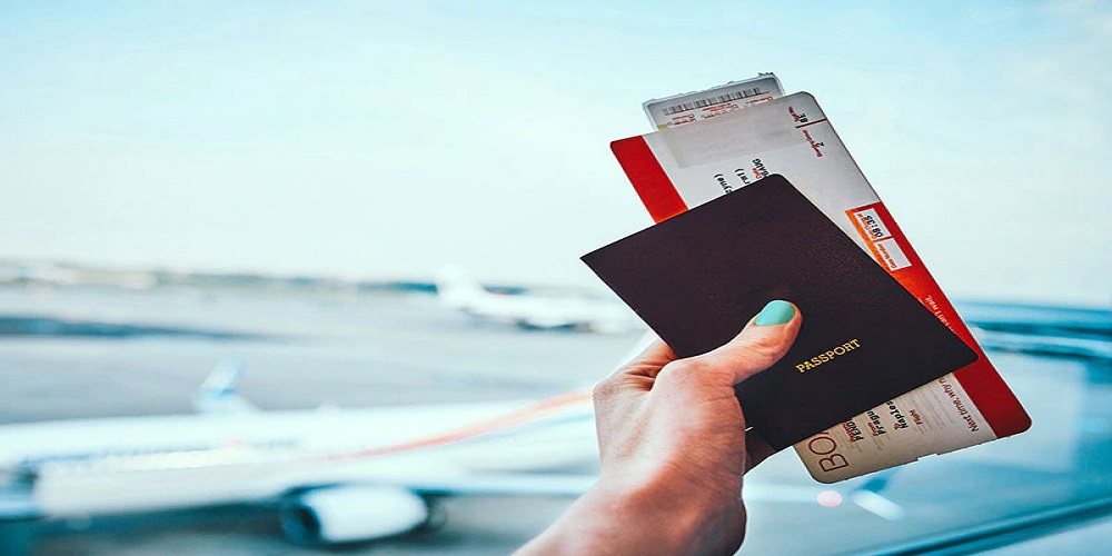 A hand holding a passport and boarding documents at an airport